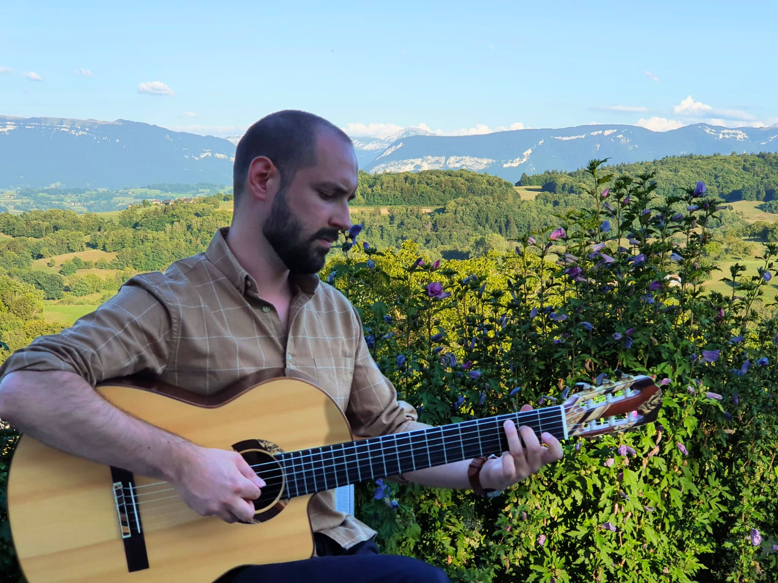maxime taudiere en concert avec sa guitare après un stage devant un magnifique paysage dans les montagnes